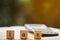 Wooden blocks with the word TAX and blurred calculator with blurred green background.