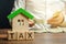 Wooden blocks with the word Tax, house with money in the hands of a businessman. The concept of paying tax for housing and