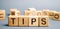 Wooden blocks with the word Tips and randomly scattered cubes. Award for good service in the cafe restaurant. A gratuity is a sum