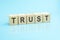 wooden blocks with the word Trust, blue background