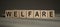 A wooden blocks with the word WELFARE written on it on a gray background