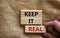 Wooden blocks with words `keep it real`. Beautiful canvas background, male hand. Copy space. Business concept