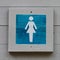 A wooden blue female bathroom sign