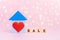 Wooden blue house with red heart and with text Sale on pink bokeh background with copy-space. Concept rental, construction and