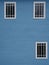 Wooden blue wall of a building with three framed windows