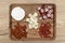 A wooden board with delicacies on which pieces of meat and various types of cheese lie, on the kitchen counter, top view.