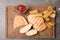 Wooden board with grilled meat, garnish and sauce on grey background