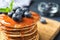 Wooden board with pancakes, syrup and blueberries on table