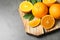 Wooden board with ripe oranges on grey. Space for text