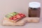 On a wooden Board is a sandwich with chocolate paste, strawberries and kiwi. Next to it is a can of chocolate. Sweet Breakfast, a