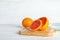 Wooden board with sliced orange revealing tomato inside on table.