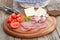 Wooden board with sliced tomatoes, cheese, and meats on a picnic table