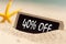 Wooden board on sunny sandy beach  with text 40% off