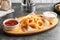 Wooden board with tasty onion rings and sauces