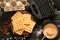 Wooden board with tasty waffles, maker machine and bowl with batter on dark wooden table