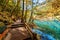 Wooden boardwalk leading along azure lake among fall woods