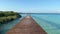 Wooden boardwalk leads to tropical cabana hut at end looking over serene ocean