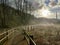 Wooden boardwalk at the nature park. Outdoor walk after the rain. Walk path makes a curve