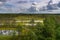 Wooden boardwalk nature trail leading through a peat bog landscape with sparse trees