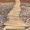 Wooden boardwalk on tropical beach pebble. floor and sand