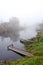 Wooden boat and bridge on river sunken in fog