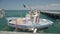 Wooden boat with fishing equipment on deck floating on waves near pier