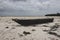Wooden boat on low tide. Zanzibar beach with old nautical vessel. African seascape with cloudy sky. Empty coast of Indian Ocean.