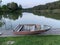 Wooden boat on the pier on the background of the lake. Fishing boat on the shore of a forest reservoir. The boat is tied off the