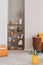 Wooden bookshelf with flowers and accessories in the corner of grey living room interior