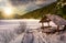 Wooden bower in snowy winter forest at sunset