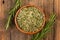 A wooden bowl filled with whole dried rosmary and two rosemary twigs