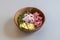 wooden bowl with Hawaiian poke bowl recipe with red tuna, sliced avocado, red onion, wakame seaweed and poppy