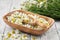 Wooden bowl of plucked daisy flowers, wooden scoop of Chamomile buds and bunch of daisy flowers on white wooden table.