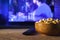 A wooden bowl of popcorn and remote control in the background the TV works. Evening cozy watching a movie or TV series at home