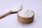 Wooden bowl and spoon of natural starch on white tiled table, closeup