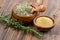 A wooden bowl with whole dried rosemary with a spice shovel, a fresh rosemary twig and a small wooden bowl filled with ground rose