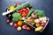 Wooden box with autumn harvest farm vegetables and root crops on black kitchen table top view. Healthy and organic food.