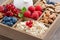 Wooden box with breakfast items - oatmeal, granola, nuts, berry