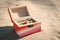 Wooden box in color of lesbian flag with golden wedding rings on sandy beach