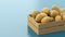 Wooden box with polygonal potatoes on a blue background. The concept of selling vegetables, healthy food, seasonal