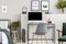 Wooden box under single metal bed with blue sheets and green blanket in trendy kid`s room with workspace