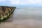Wooden breakwater covered with moss, arranged in a row at sea, long exposure time, blurred sea waves.