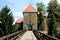 Wooden bridge entrance to old stone castle with dilapidated facade and completely new renovated roof surrounded with trees