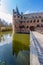 Wooden bridge over the moat with Het Oude Loo castle tower reflected on the water surface