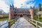 Wooden bridge over the moat, leading to the gate to Het Oude Loo castle surrounded by trees