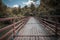 Wooden bridge over river leading to forest and sky background