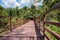 Wooden bridge over river leading to forest and sky background