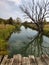 Wooden bridge and tree are reflected in the river in autumn