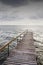 Wooden bridge on wavy lake. Dark sky before storm