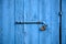 Wooden bright blue, empty, old door for background. Rusty latch, padlock. Close up, banner, details